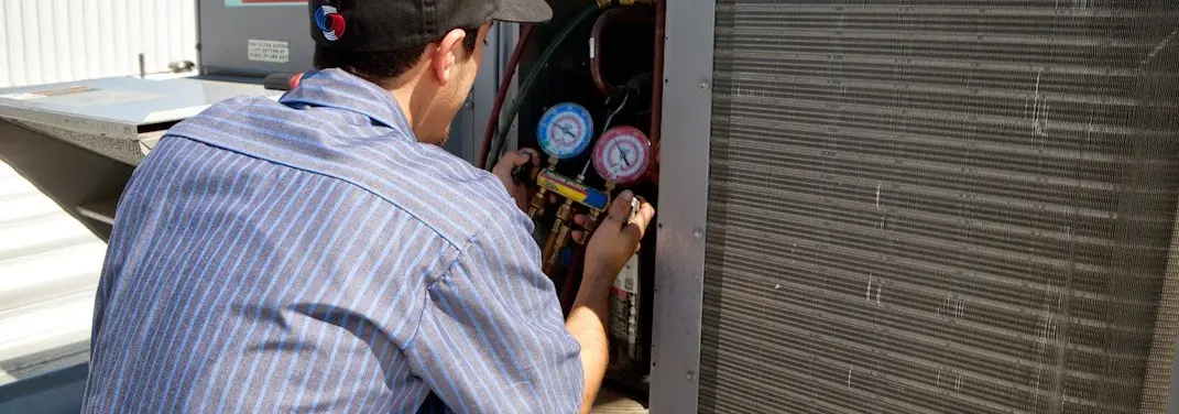 HVAC technician servicing a condenser unit in Justin